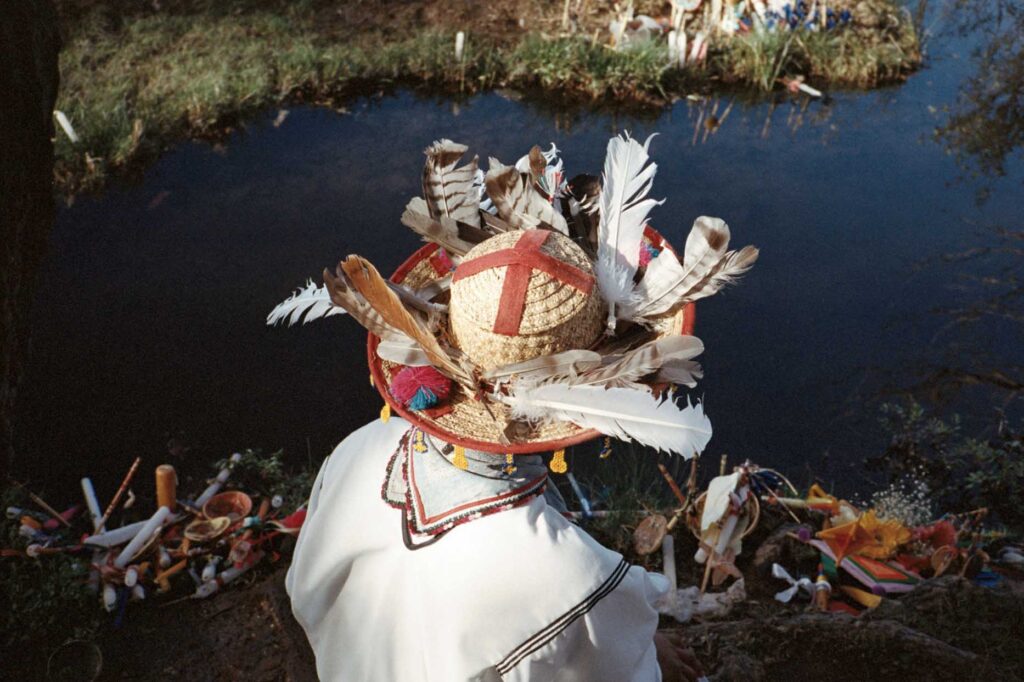 man in hat with feathers looking at river