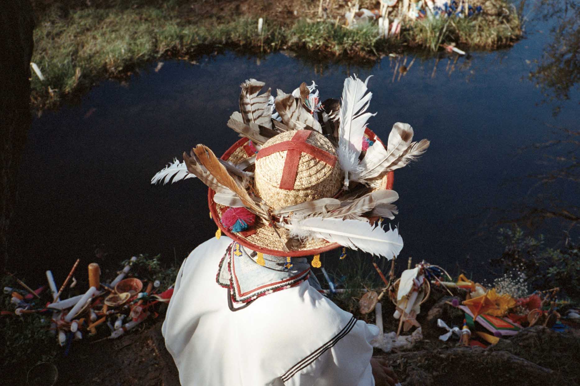 man in hat with feathers looking at river