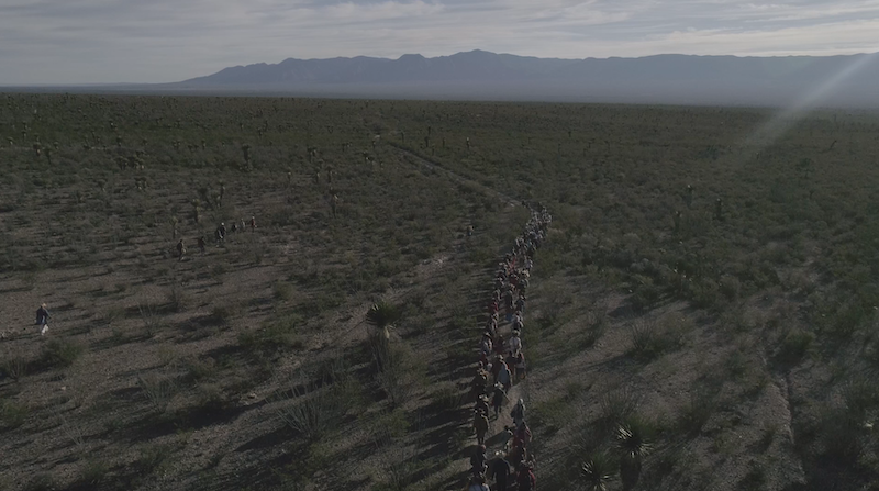 A line of people walking through a dry valley